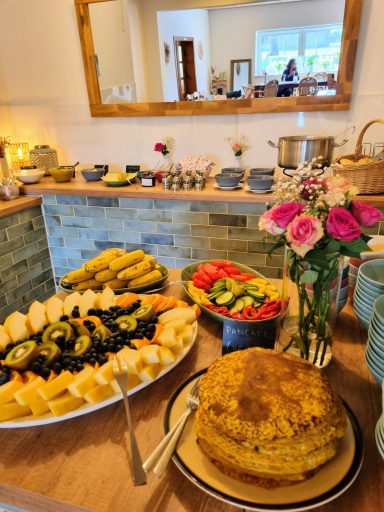 Liebevoll angerichtetes Frühstücksbuffet mit frischem Obst, Pancakes, Gemüse und hausgemachten Speisen im Seminarhaus House of Flow.