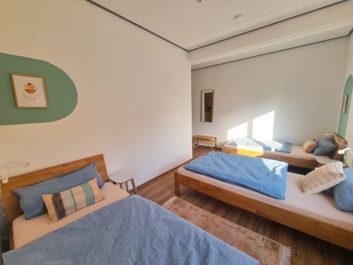 Dreibettzimmer mit drei Einzelbetten, hellen Farben und Blick in den Innenhof.