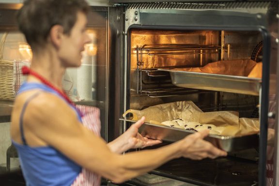 Kathrin schiebt frisch gebackene Brötchen in den Ofen im House of Flow, Retreat Brandenburg