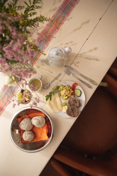Frühstücksteller mit Rührei, Käse, Gemüse, frischen Brötchen und Tee, dekorativ angerichtet im House of Flow, Retreat Brandenburg