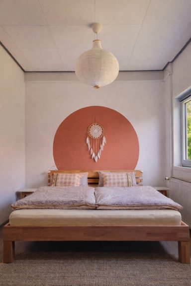 Großes Doppelbett im Vierbettzimmer mit warmer Wandfarbe und natürlicher Einrichtung.