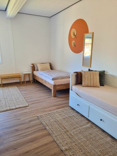 Zwei Einzelbetten im Vierbettzimmer mit warmen Farben und natürlicher Einrichtung.