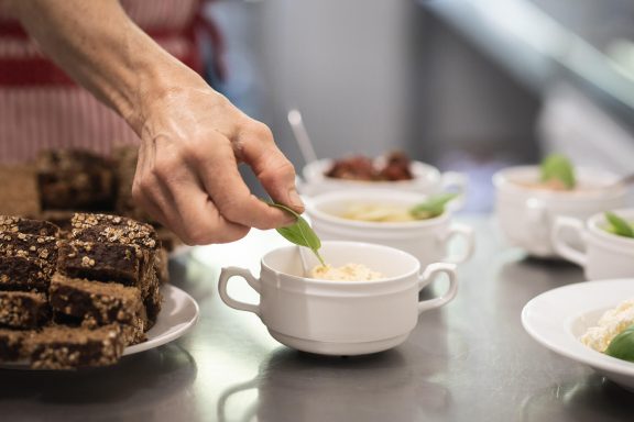 Hausgemachte Aufstriche und geschnittenes Brot im House of Flow, Kathrin dekoriert gerade mit Basilikum, Retreat Brandenburg