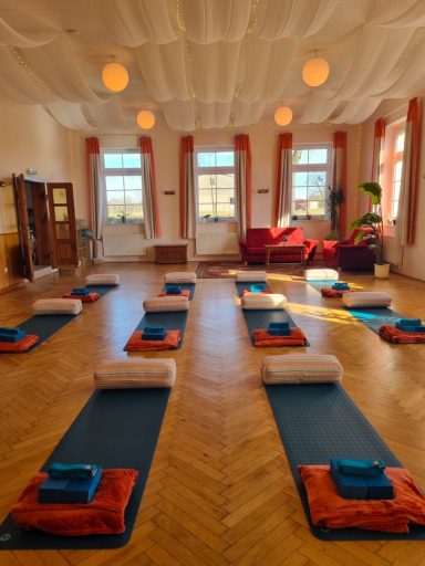 Seminarraum mit ausgelegten Yogamatten, Bolstern und Blöcken für eine Yogastunde.